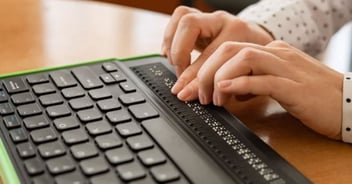 Close-up on a braille keyboard with the hands of a person using it