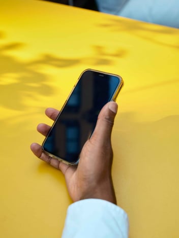 a hand and a smartphone on a yellow background