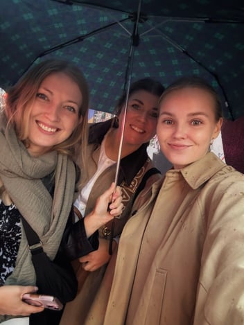 three ladies under an umbrella, smiling