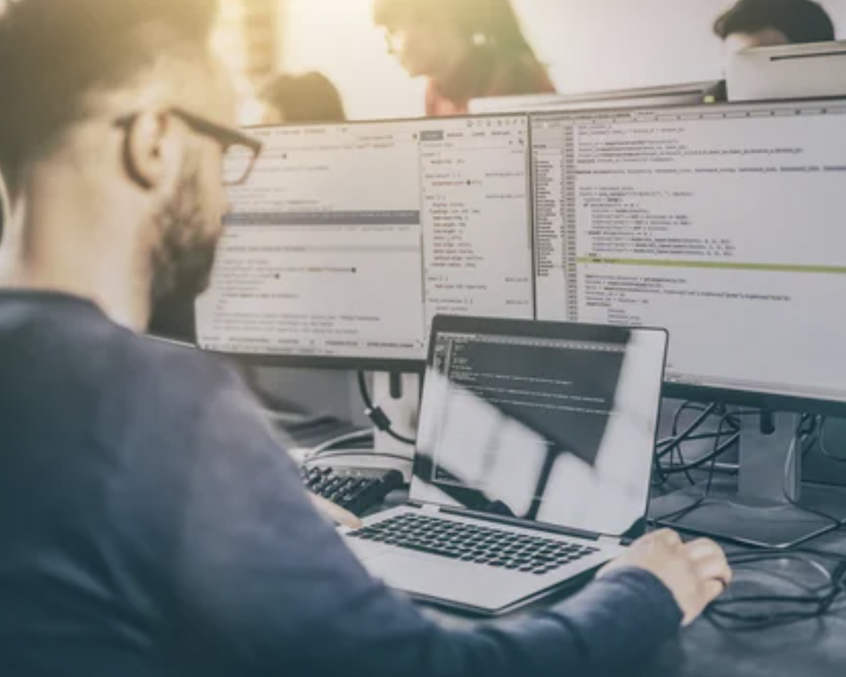 Image of a man writing software on a laptop.