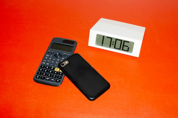 Table clock, phone and calculator on a table