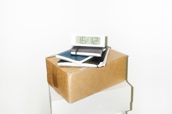 Cardboard boxes with notebooks and clock on top