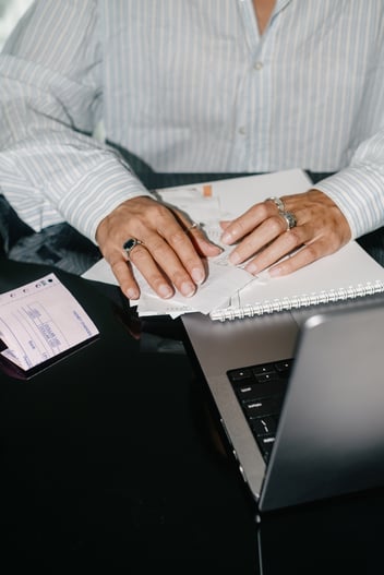 Person writing in notebook in front of a laptop