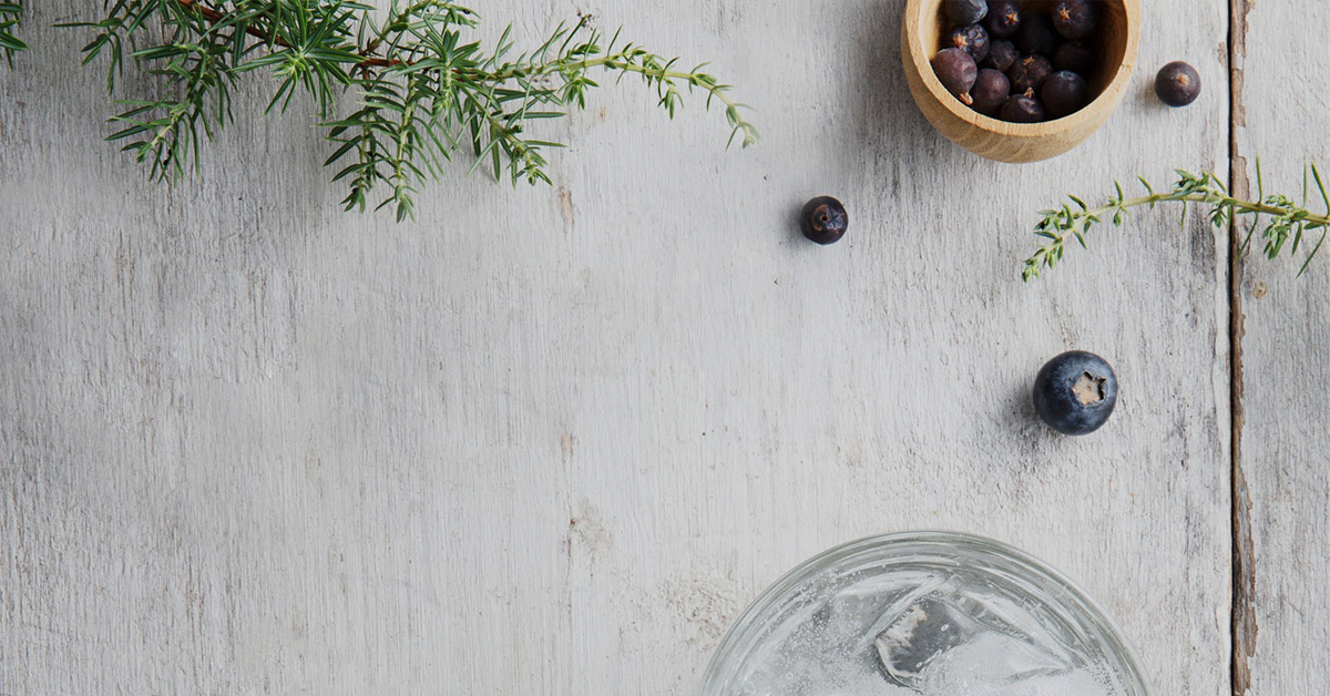 Picture of a glass, some herbs and berries on a table