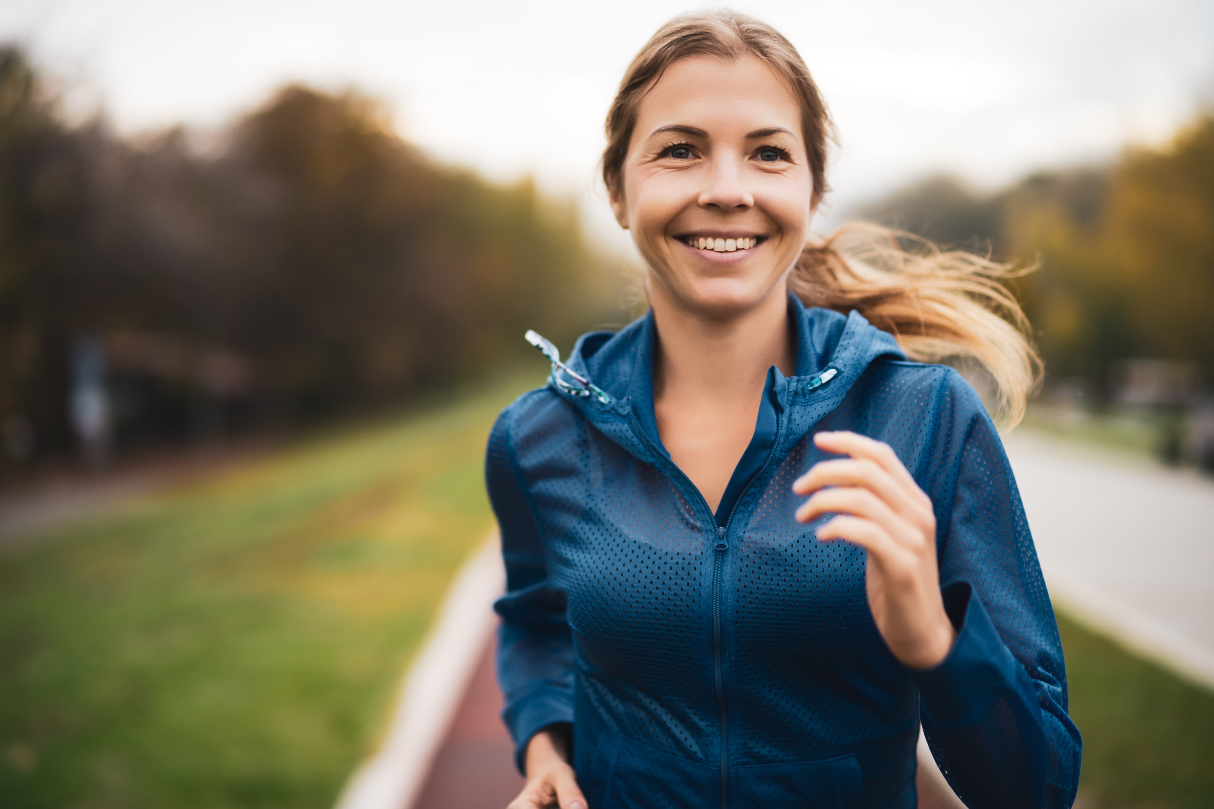 A woman running and smiling on a blue jersey