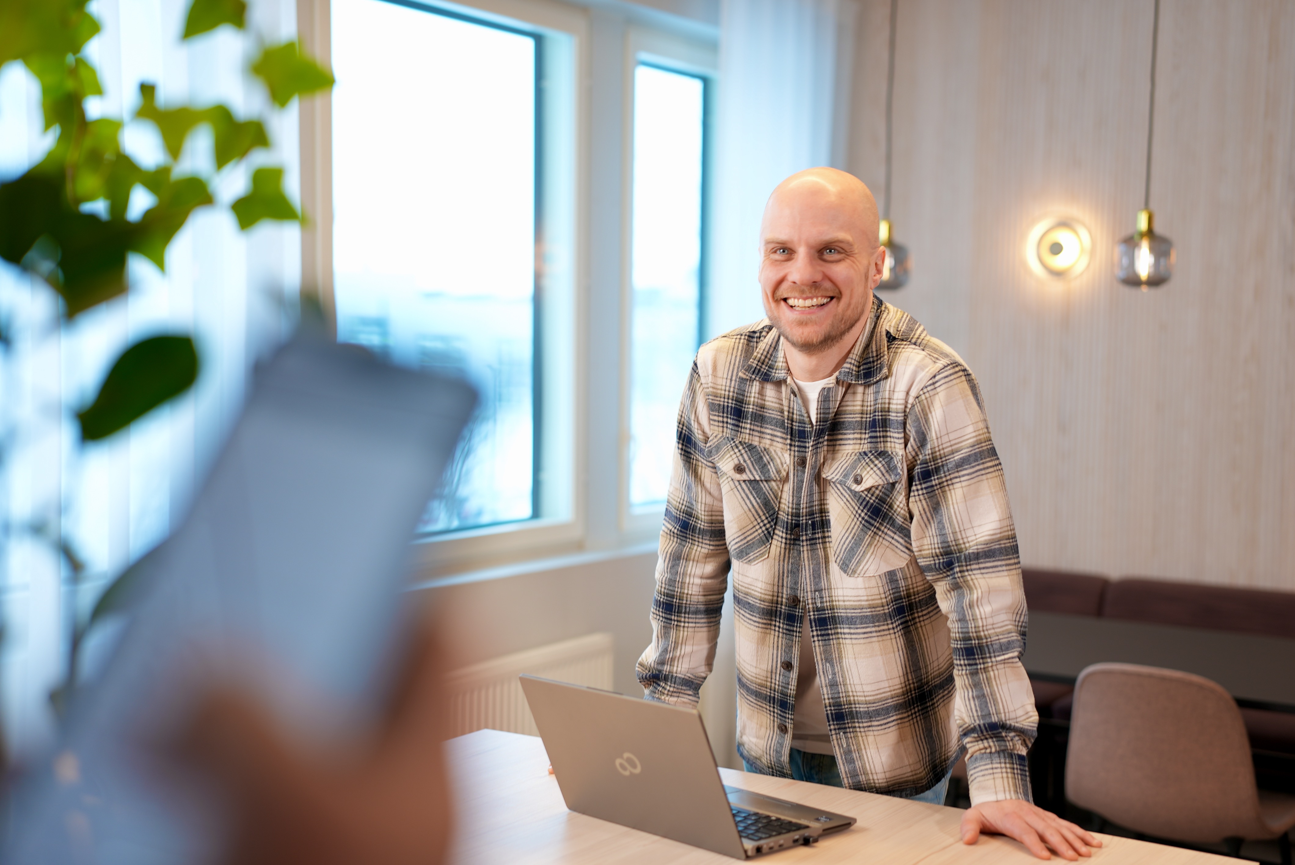 A man smiling for camera, laptop in front of him