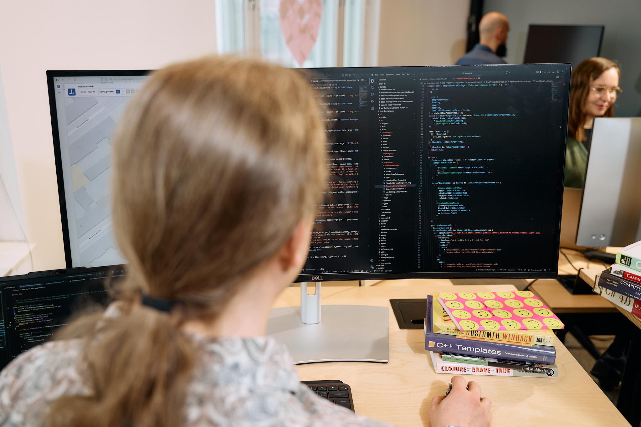 A developer with long hair on a ponytail coding on his desk