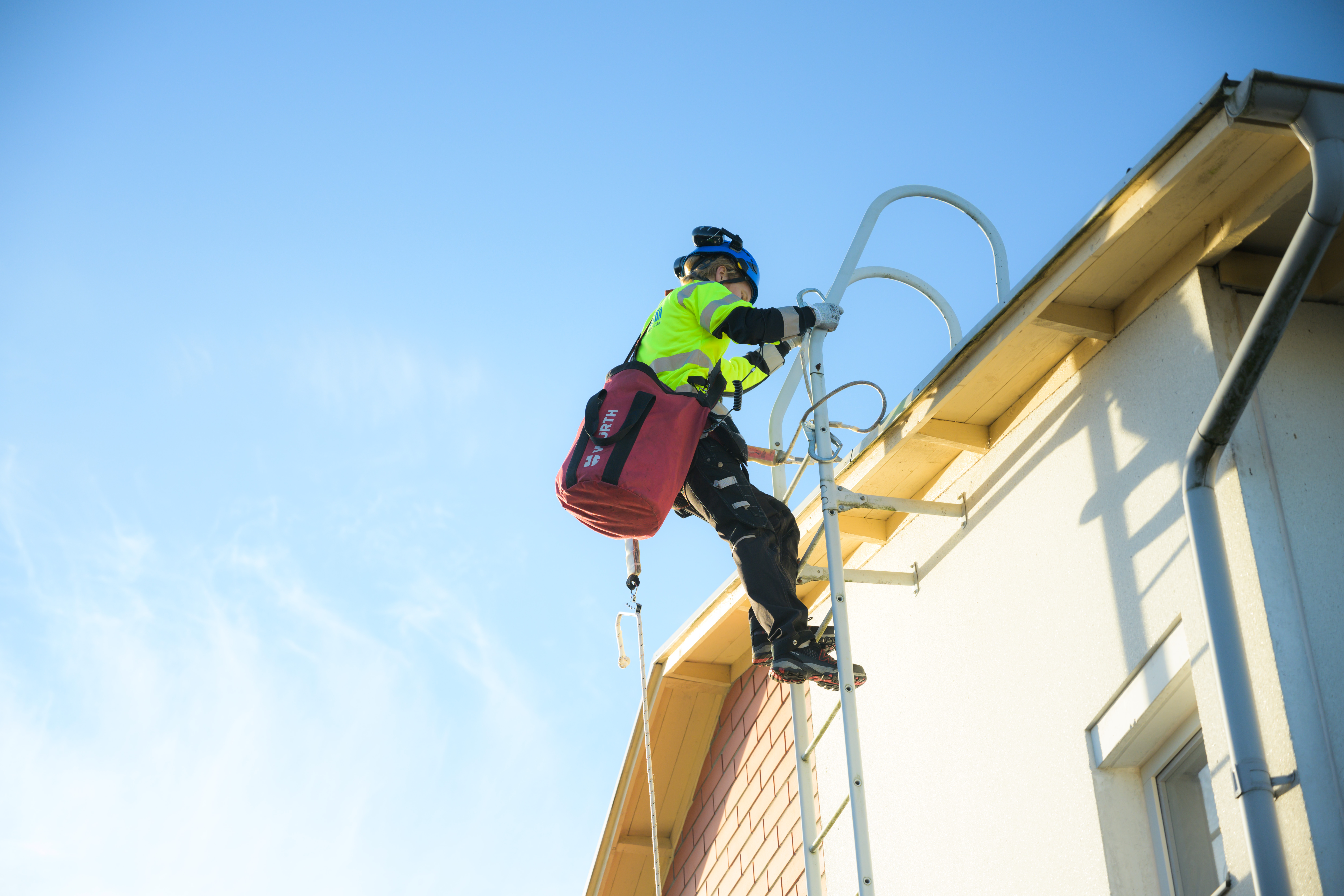 A construction worker climbing on a roof