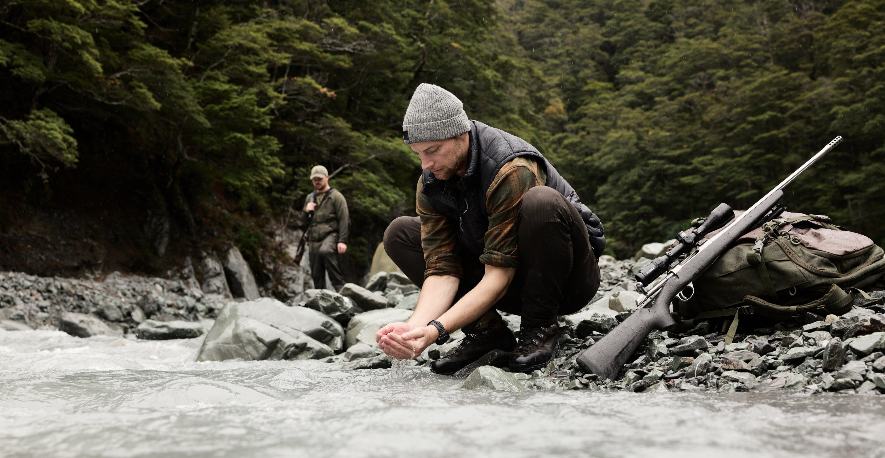 A person taking water from the river with his bare hands. 